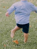 Two adults and a child dance barefoot in the grass.