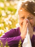 Girl sitting in a meadow with dandelions and has hay fever or allergy