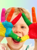 Child laughing with multi-colored paint on his hands