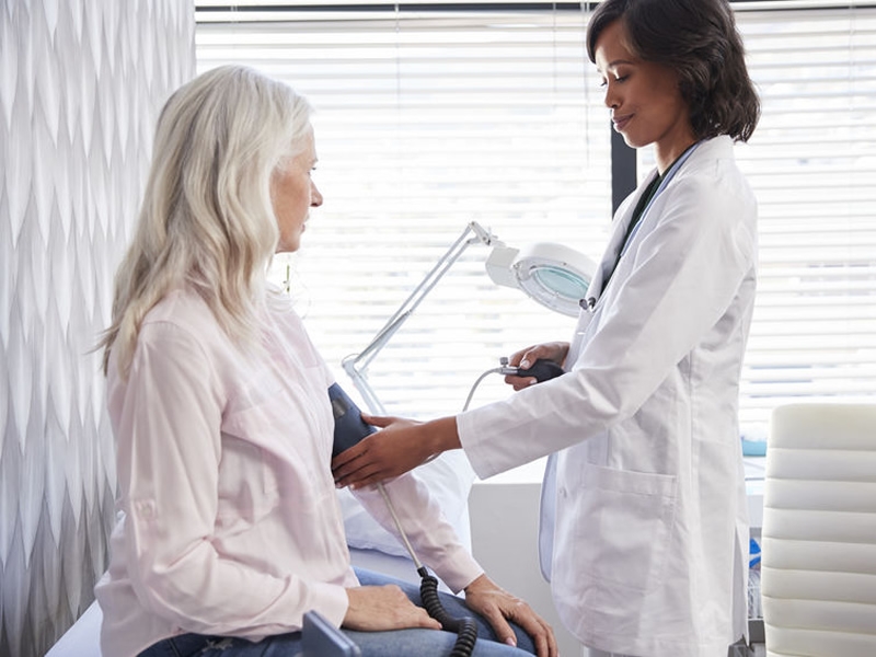 Woman patient having blood pressure taken by female doctor in office