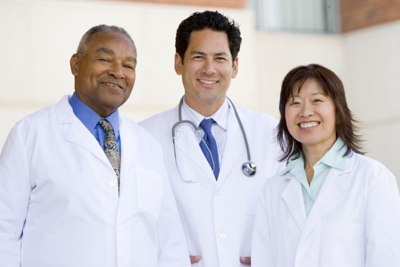 Three doctors standing outside a hospital