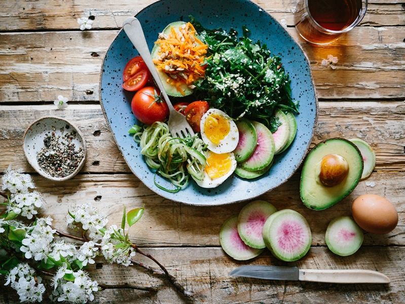 Eggs, tomato, avocado, shredded carrots, zucchini spirals, and spinach on a plate 