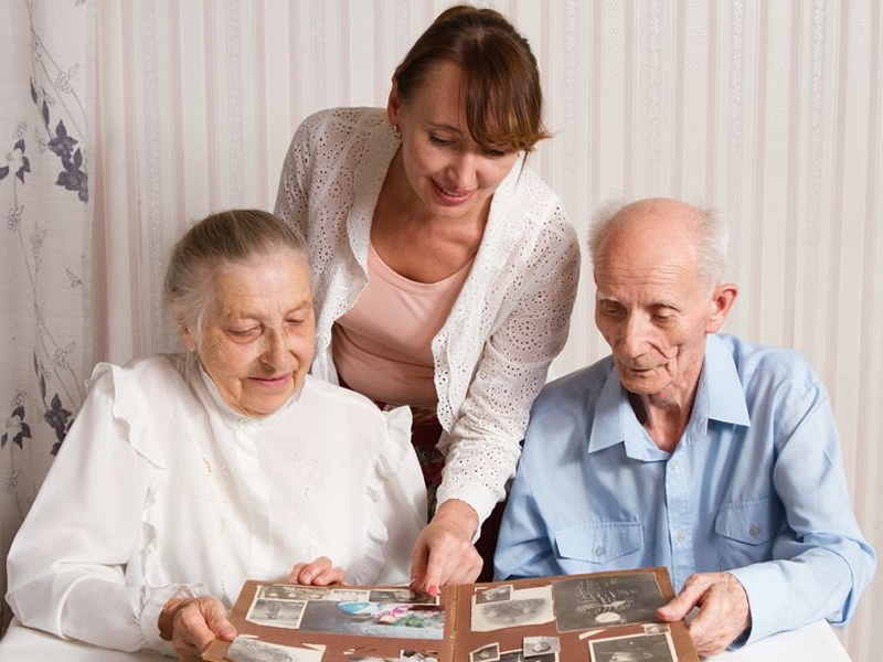 caregiver looks at photo book with an elderly couple