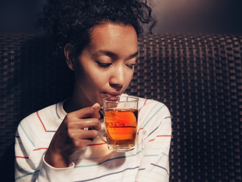 woman drinking a cup of tea in a clear mug