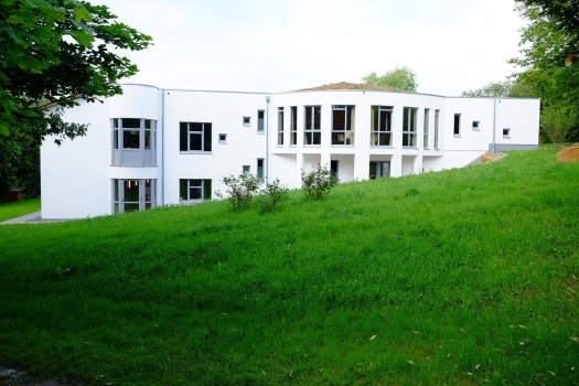 White clinic building with large windows surrounded by green grass