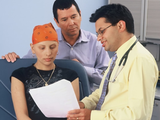 A doctor discusses medical information with a teenage girl, who is wearing a head scarf, and her father.
