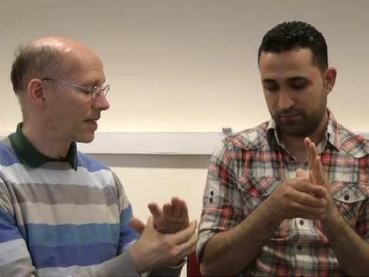 two men seated using EFT on their hands