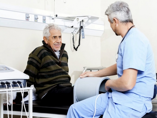 Senior man receiving relectromagnetic therapy for knee from doctor
