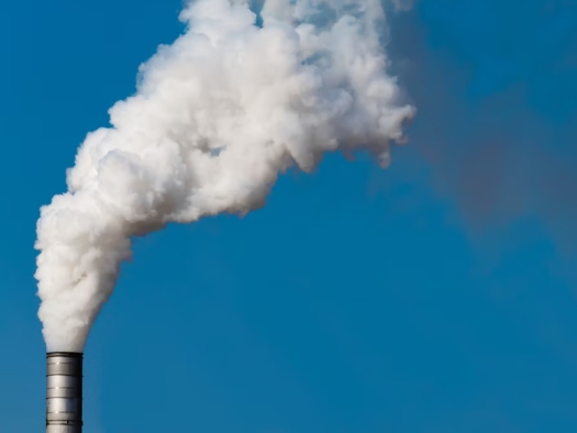 smoke stack billowing out a white cloud against a blue sky