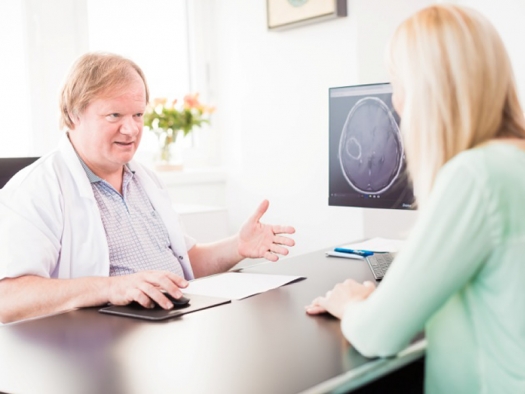 doctor meeting with patient at desk with CT scan on computer screen