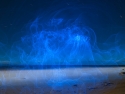 Aether - long exposure of blue electroluminescent wire creating ethereal ghost-like pattern in dark sky over water