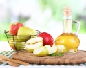 Apple cider vinegar in glass bottle and ripe fresh apples on wooden table