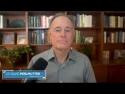 David Perlmutter seated in front of microphone with wood bookcases behind him
