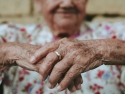 elderly hands folded in front of a person blurred in the background
