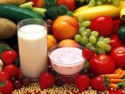 glass of milk, dish of yogurt surrounded by fresh fruit and vegetables
