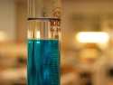 blue liquid in test tube; blurred science lab in background
