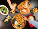people reaching for salad, bread, fruit, finger food on table