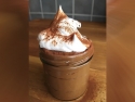 chocolate mousse in clear glass jar with whipped cream on top sprinkled with cinnamon