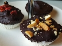 Coconut bars in muffin papers topped with chocolate on plate