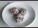 three chocolate balls rolled in shredded coconut on a white plate