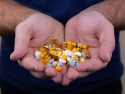A pile of multi-colored pills in a man's cupped hands.