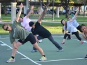 group of people participating in a stretching class outside in a park
