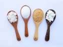 four wooden spoons with different types of sugar, granulated and cubed