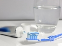 blue toothbrush, blue and white toothpaste, toothpaste tube, glass of water