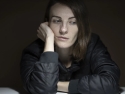 woman sitting at table with head resting on on hand, fatigued